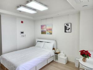 um quarto branco com uma cama e um lavatório em Sokcho Summitbay 1209 "Ocean View" em Sokcho