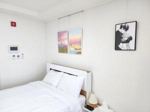 a bedroom with a white bed and three pictures on the wall at Sokcho Summitbay 1209 "Ocean View" in Sokcho