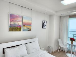 a white bedroom with a bed and a table at Sokcho Summitbay 1209 "Ocean View" in Sokcho