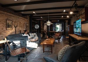 a woman sitting on a couch in a living room at Pyur Otel by Ombra House in Chiang Mai