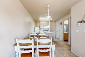 a kitchen with a table and some white chairs at Harbor Village Pool Building Condo 104 in Garden City