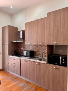 a kitchen with wooden cabinets and a sink and a microwave at Luisa Apartments in Naples
