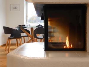 een open haard in een woonkamer met een tafel en stoelen bij Apartment Alpes et Lac 40 by Interhome in Champex