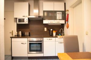 a kitchen with white cabinets and stainless steel appliances at Haus Bergheim in Saalbach Hinterglemm