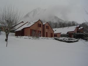 a house covered in snow with mountains in the background at Chalet de 2 chambres avec terrasse et wifi a Cauterets in Cauterets