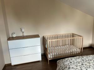 ein Kinderbett in einem Schlafzimmer mit einer Kommode und einem Bett in der Unterkunft Apartament Bobrzańska in Świdnica