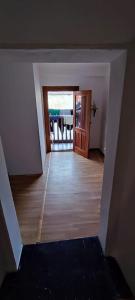 um quarto vazio com um corredor com uma porta e um piso de madeira em Rincon de Valdaliga em Valdaliga 