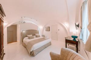 a white bedroom with a bed and a chair at Antica Rheginna Luxury Room in Minori