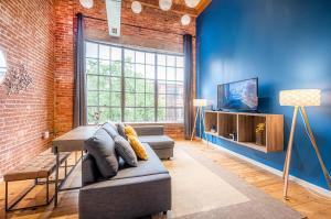 een woonkamer met blauwe muren en een bank en een tv bij 100 Year Old Historic Brick 2BR Loft High Ceiling3 in Durham
