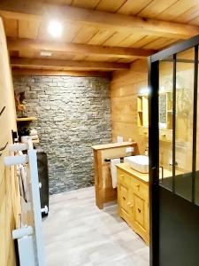 baño con pared de piedra y lavamanos en DEL VINO bar à vin & guitares, en Orchamps-Vennes