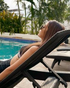 une femme assise sur une chaise près d'une piscine dans l'établissement Hotel Rega Suites Guayabitos - Family & Kitchen, à Rincon de Guayabitos