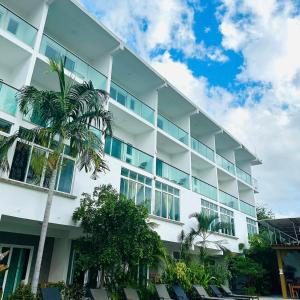 a white building with a palm tree in front of it at Hotel Rega Suites Guayabitos - Family & Kitchen in Rincon de Guayabitos