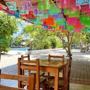 uma mesa de madeira e duas cadeiras sentadas sob um guarda-sol em Hotel Rega Suites Guayabitos - Family & Kitchen em Rincón de Guayabitos