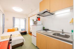 cocina pequeña con fregadero y cama en KYARA Hotel 402, en Tokio