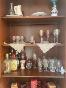 un estante con copas de vino y otros artículos. en Ground floor apartment with gym & yard in Paggaio, en Próti