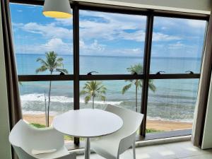 a table and chairs in a room with a view of the ocean at Flat Frente Mar + Limpeza | R601 in Maceió