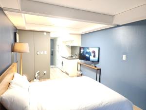 a bedroom with a white bed and a television at Sokcho Marinabay 305 "Lake View" in Sokcho