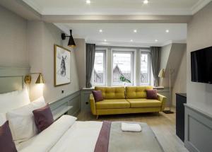 ein Wohnzimmer mit einem gelben Sofa und einem TV in der Unterkunft Krupówki 17 Resort & SPA in Zakopane