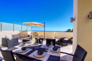 een eettafel met stoelen en een parasol op een patio bij 1090 amazing panorama sea view penthouse large terrace heated pool gym in Marbella