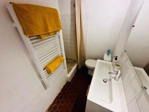 a bathroom with a sink and a toilet and yellow towels at La Bohème : Gardon et Pont Du Gard in Remoulins