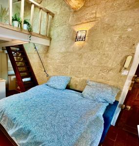 a bedroom with a blue bed in a stone wall at La Bohème : Gardon et Pont Du Gard in Remoulins