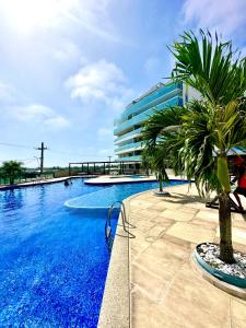 uma piscina com palmeiras em frente a um edifício em Apartamento até 8 Pessoas Praia Grande - Le Bon Vivant em Arraial do Cabo