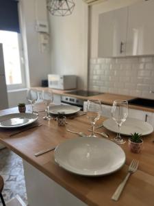 uma mesa com pratos brancos e copos de vinho em Duplex avec Clim centre de nimes em Nîmes