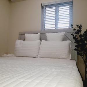uma cama branca com almofadas brancas e uma janela em Villa By The Bay em Nassau