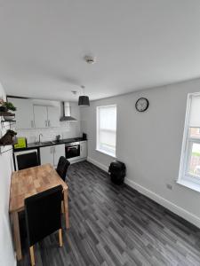 a kitchen and dining room with a table and a clock on the wall at Harbour Flats in Skegness