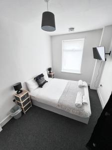 a white bedroom with a bed and a window at Harbour Flats in Skegness