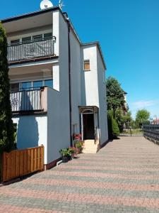 uma casa branca com uma varanda e uma entrada em Apartamenty Eka Dom Gościnny em Rewal