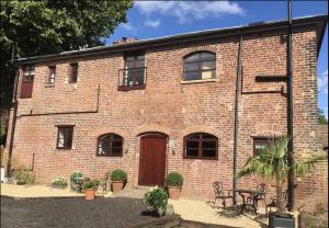 a brick building with a wooden door and a table at Evelith Manor Barns in Shifnal