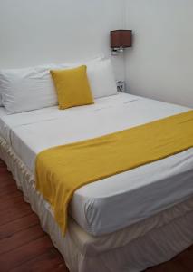 ein großes weißes Bett mit einer gelben Decke darauf in der Unterkunft Rainbow Inn in Grand Bras