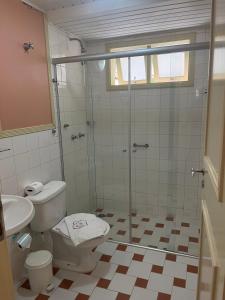 a bathroom with a shower and a toilet and a sink at Pousada Vila das Cores in Campos do Jordão