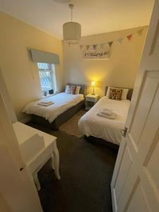 a bedroom with two beds and a table and a window at Bronte Bungalow - In Beautiful Bronte Country! in Oxenhope