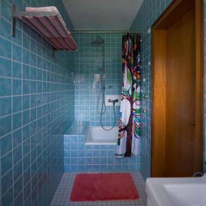 uma casa de banho em azulejos azuis com um chuveiro e um lavatório. em Ferienwohnung Lisa em Freisen