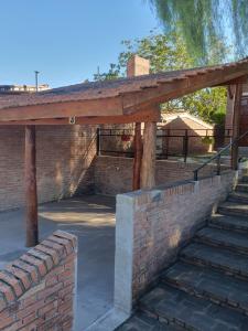 a brick retaining wall with a wooden pergola at El Aguaribay de los Nonos in Mina Clavero