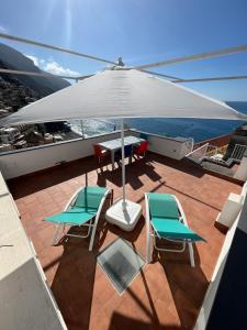 eine Terrasse mit einem Tisch, Stühlen und einem Sonnenschirm in der Unterkunft Casa Positano in Positano