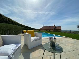 eine Terrasse mit einem Sofa und einem Tisch neben einem Pool in der Unterkunft AZIENDA AGRICOLA CA' LUNGA in Cinto Euganeo