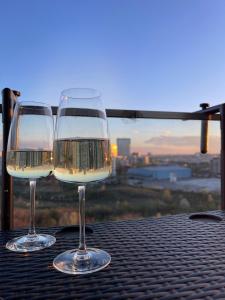 dos vasos de vino blanco sentados en una mesa en Apartament Panoramic View I Refugiu la înălțime, en Bucarest