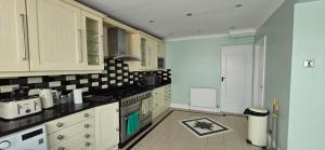 una cucina con armadietti bianchi e ripiani neri di Avala, 5/6 Bed House in Romford a Great Warley Street