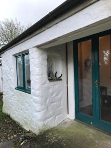 un edificio blanco con una puerta verde y una ventana en Tiny Cosy Snug, en Pembrokeshire