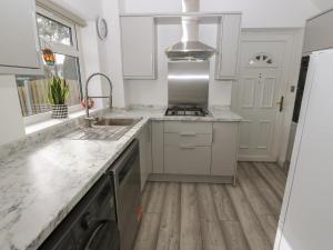 een witte keuken met een wastafel en een fornuis bij Cosmic Pearl in Garforth