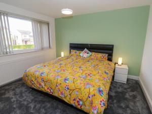 a bedroom with a bed with a yellow comforter and a window at Cosmic Pearl in Garforth