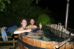 a man and woman holding glasses of wine in a barrel at Parque Guaiquivilo, Cabañas de montaña con tinaja privada in Colbún