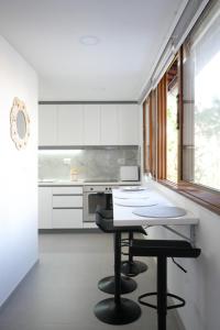 a kitchen with white cabinets and a table and stool at SHANO'S Apartment - Free Parking in Sarandë