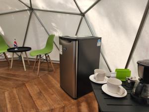 a refrigerator in a tent with a table and chairs at Glamping Naioth in Guápiles