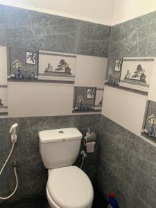 a bathroom with a white toilet and some pictures on the wall at Nesan’s villa in Trincomalee
