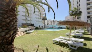 Un grupo de sillones blancos y una sombrilla. en Al Charb TopFloor sea view, ar con, pool - CleverDetails, en Vilamoura