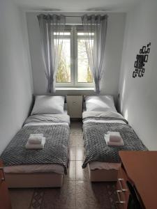 two beds in a small room with a window at Apartament Mickiewicza w centrum Augustowa in Augustów